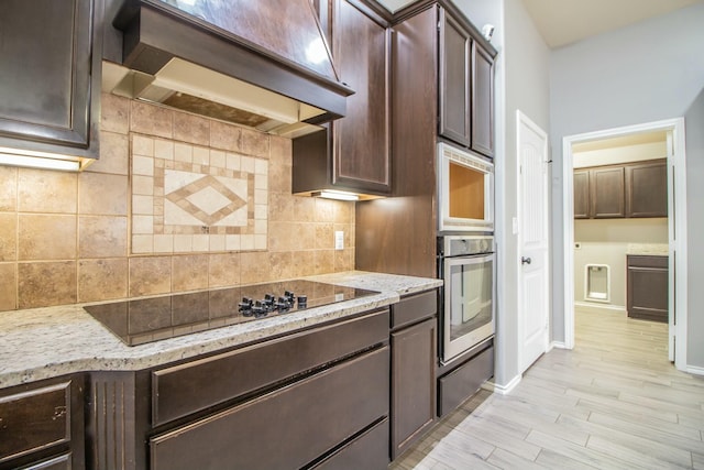 kitchen with custom range hood, black electric stovetop, dark brown cabinets, and decorative backsplash