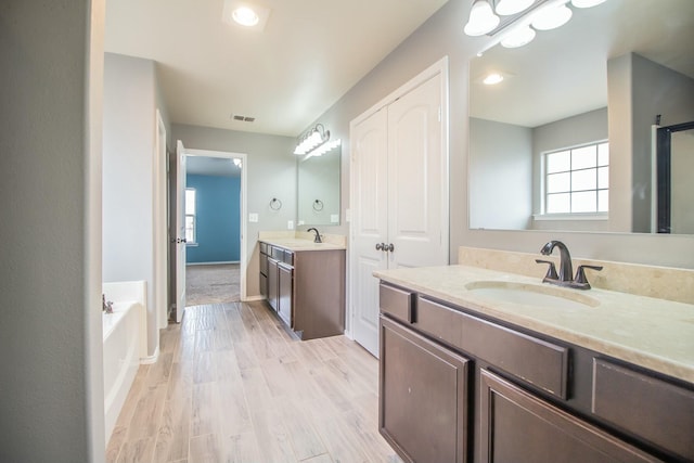 bathroom featuring a sink, visible vents, two vanities, and wood finished floors