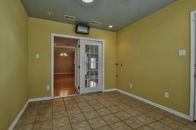 spare room with light tile patterned floors and an inviting chandelier