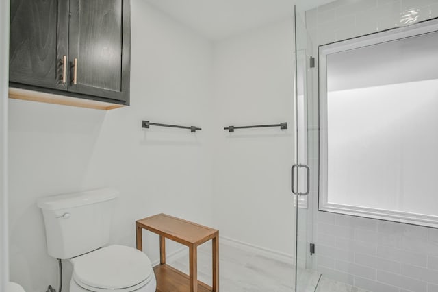 bathroom featuring a shower with shower door and toilet