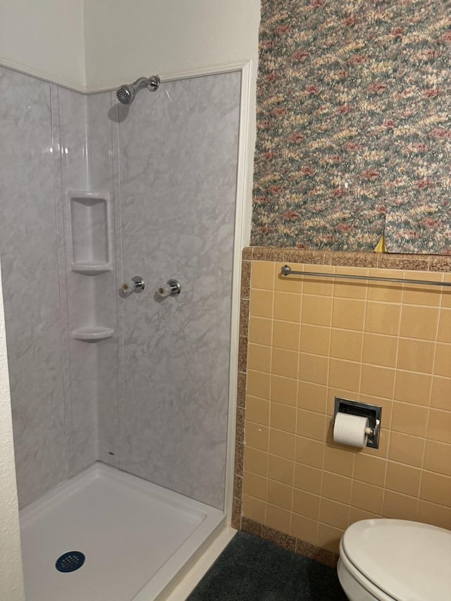 bathroom with tile walls, toilet, and walk in shower