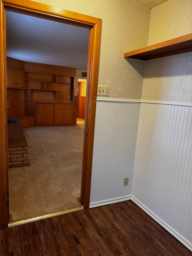 laundry area with dark wood-type flooring, built in features, and wooden walls