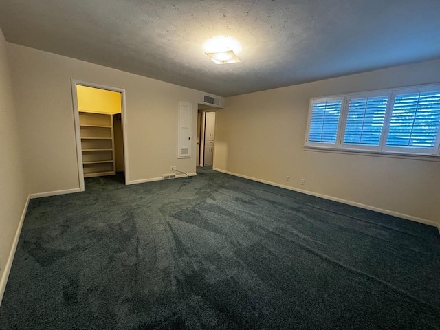 unfurnished bedroom with dark carpet, a closet, and a textured ceiling