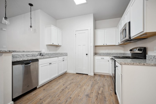 kitchen featuring appliances with stainless steel finishes, white cabinets, hanging light fixtures, light hardwood / wood-style floors, and light stone countertops