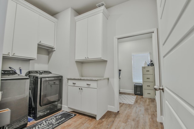 laundry area featuring washer and clothes dryer, visible vents, cabinet space, light wood-style flooring, and baseboards