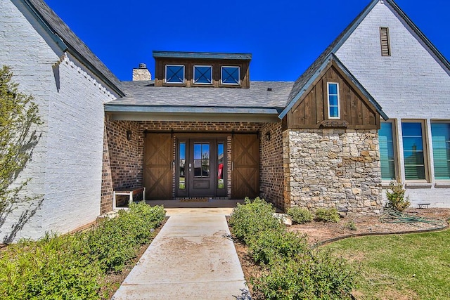 entrance to property featuring stone siding, a chimney, and brick siding