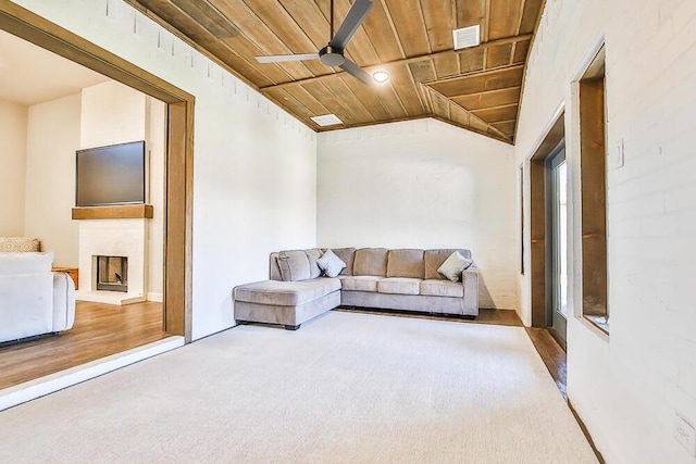 living area with a ceiling fan, wood ceiling, carpet flooring, a large fireplace, and vaulted ceiling