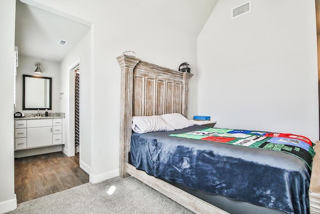 carpeted bedroom featuring ensuite bath, baseboards, visible vents, and a sink