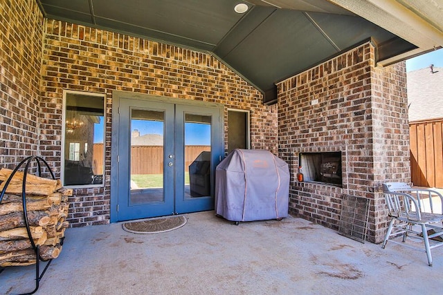 view of patio / terrace featuring an outdoor brick fireplace, french doors, and grilling area