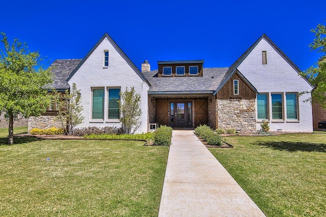 view of front of property with a front yard, stone siding, brick siding, and a chimney