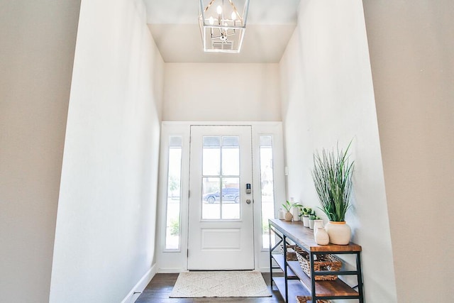 foyer entrance featuring dark wood-type flooring, baseboards, and an inviting chandelier