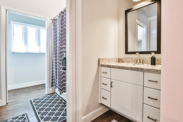 bathroom featuring a shower with curtain, baseboards, wood finished floors, and vanity