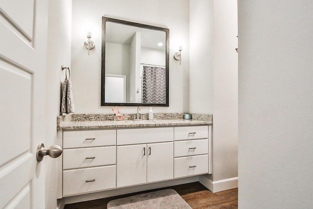 bathroom with wood finished floors, vanity, and baseboards