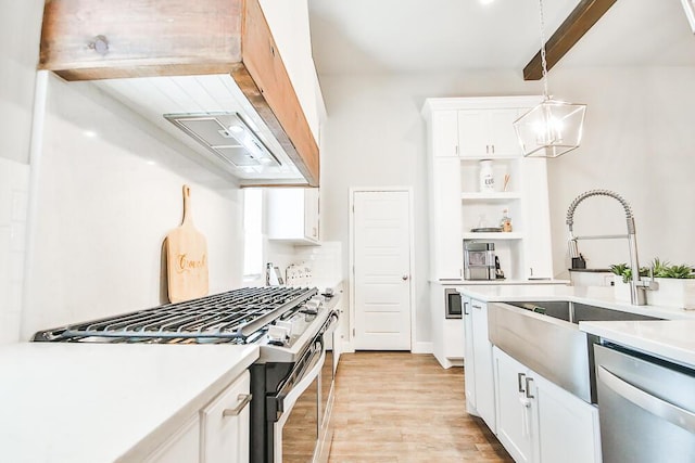 kitchen with light wood-style flooring, a sink, white cabinetry, light countertops, and appliances with stainless steel finishes