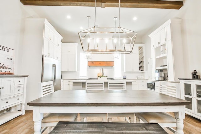 kitchen featuring stainless steel appliances, a chandelier, white cabinets, and beamed ceiling