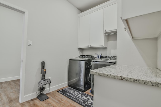 washroom featuring baseboards, light wood-style floors, cabinet space, and washer and dryer