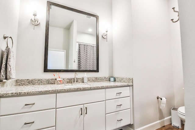 bathroom featuring vanity, toilet, and baseboards