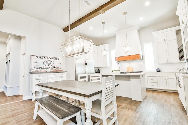 kitchen with built in refrigerator, visible vents, light countertops, beam ceiling, and light wood finished floors