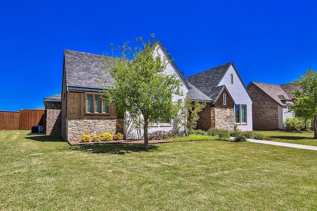 view of front facade featuring stone siding, central AC, a front yard, and fence