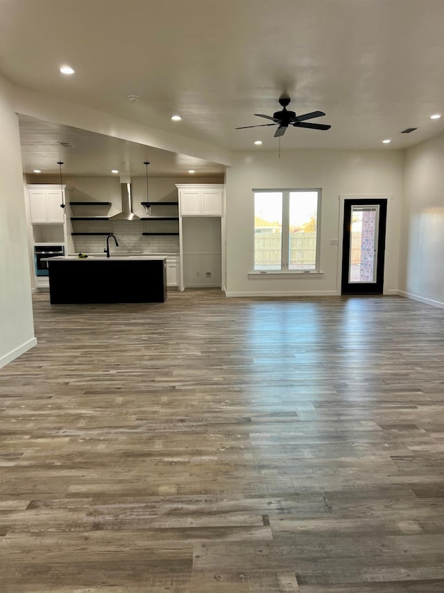 unfurnished living room featuring ceiling fan, sink, and light wood-type flooring