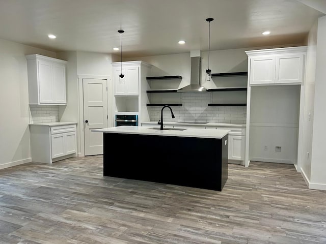 kitchen featuring sink, decorative light fixtures, white cabinets, and wall chimney exhaust hood