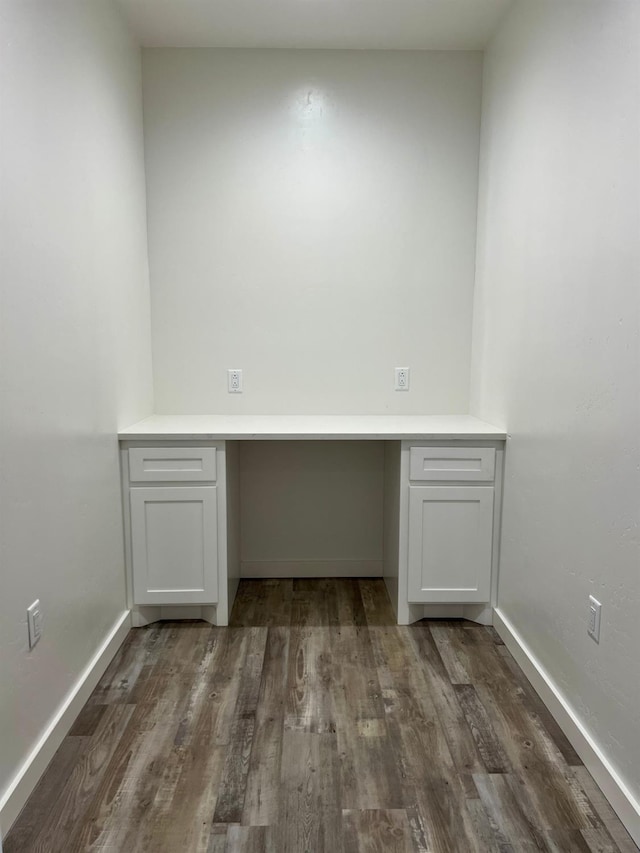 unfurnished office featuring dark hardwood / wood-style flooring and built in desk