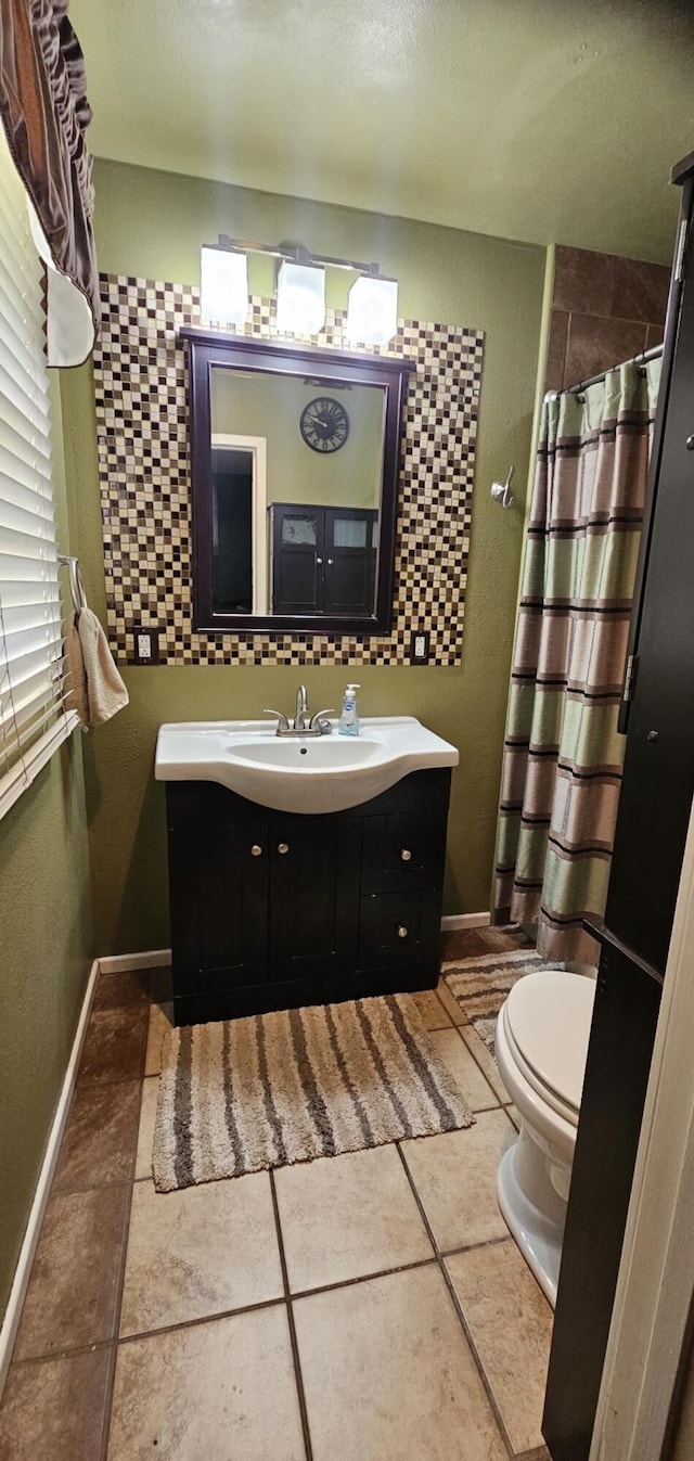 bathroom featuring toilet, curtained shower, vanity, and baseboards
