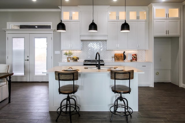 kitchen featuring white cabinetry, hanging light fixtures, a kitchen breakfast bar, and an island with sink