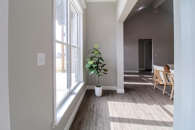 hallway featuring dark wood-style floors, a high ceiling, and baseboards