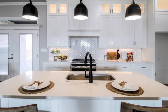 kitchen with white cabinetry, hanging light fixtures, stainless steel stove, and a breakfast bar area