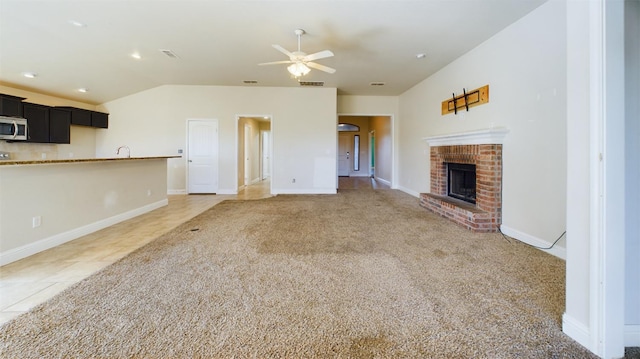 unfurnished living room featuring vaulted ceiling, ceiling fan, a fireplace, and dark carpet