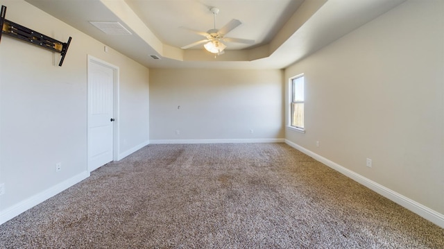 carpeted empty room featuring a raised ceiling and ceiling fan