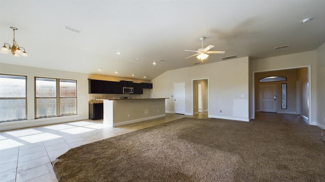 unfurnished living room with light tile patterned flooring, lofted ceiling, and ceiling fan with notable chandelier