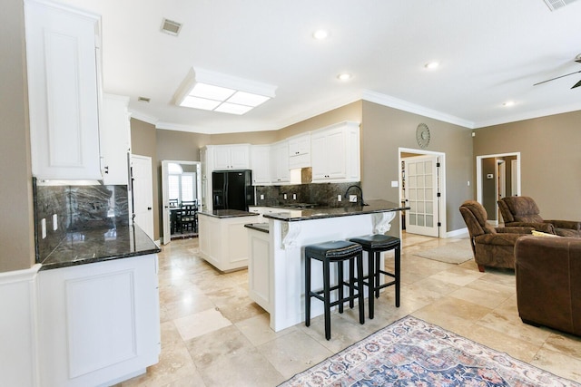 3709 156th St, Lubbock, TX 79423 - kitchen with black fridge with ice dispenser, open floor plan, tasteful backsplash, crown molding, and a peninsula