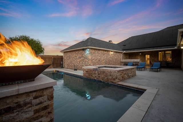 pool at dusk featuring an in ground hot tub, an outdoor fire pit, and a patio