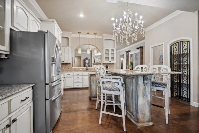 kitchen with white cabinetry, stainless steel fridge with ice dispenser, a breakfast bar area, and pendant lighting