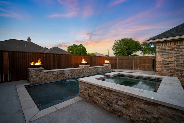 pool at dusk featuring an in ground hot tub