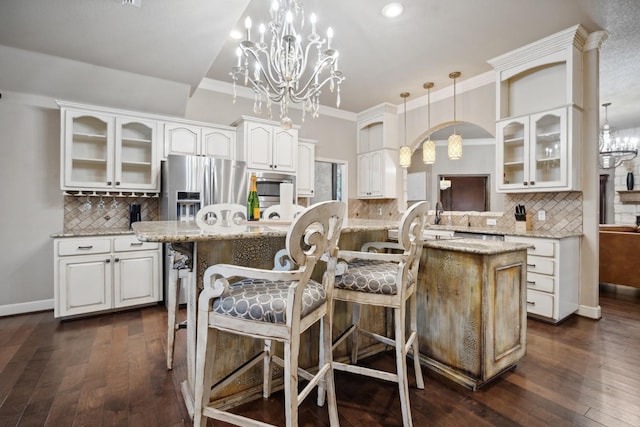 kitchen with a kitchen island, pendant lighting, white cabinetry, a kitchen bar, and stainless steel refrigerator with ice dispenser