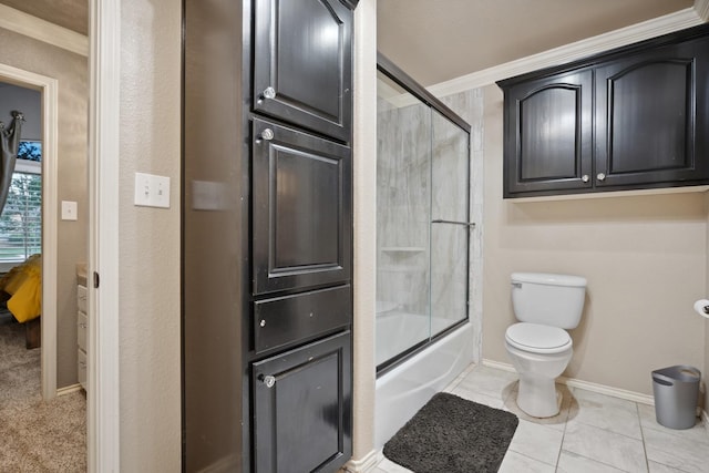 bathroom featuring tile patterned flooring, ornamental molding, combined bath / shower with glass door, and toilet