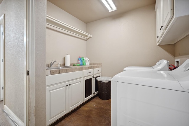 laundry area featuring separate washer and dryer, sink, and cabinets