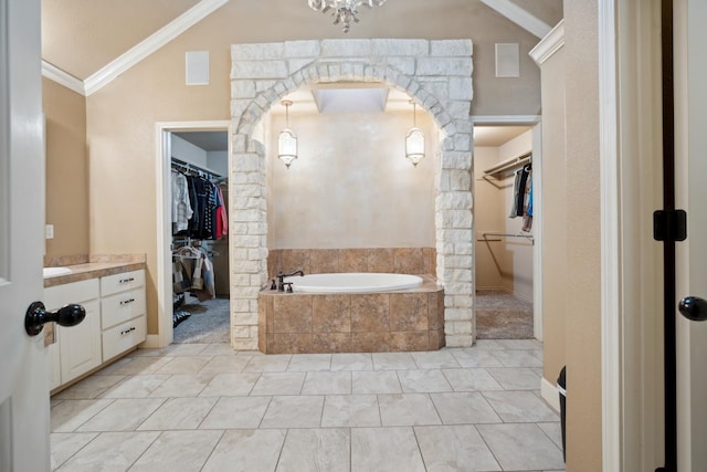 bathroom featuring tiled tub, crown molding, lofted ceiling, and vanity