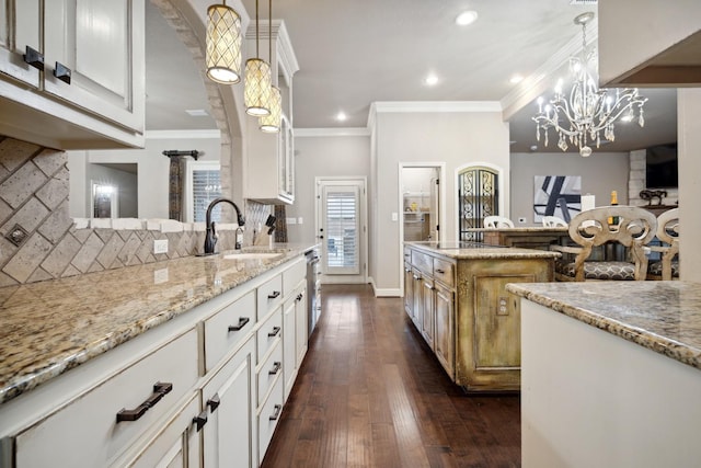 kitchen with white cabinetry, light stone countertops, sink, and hanging light fixtures