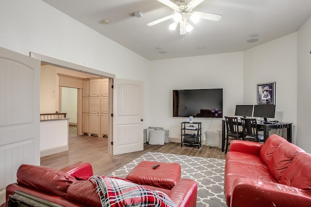 living room with baseboards, light wood-type flooring, ceiling fan, and lofted ceiling