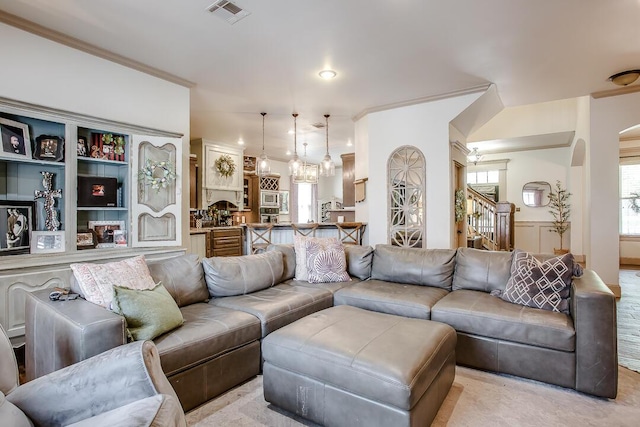 living room featuring ornamental molding, visible vents, and stairway