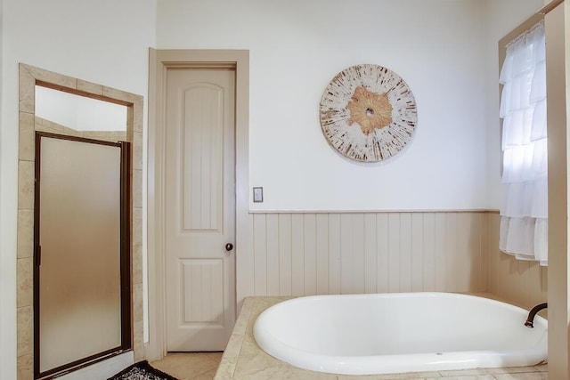 full bathroom with a garden tub, a shower stall, and a wainscoted wall