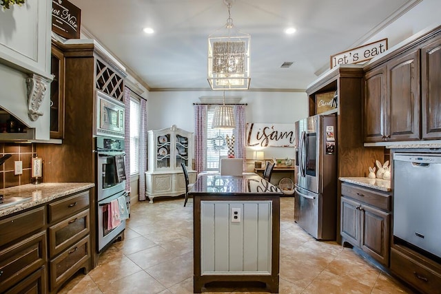 kitchen featuring light stone counters, crown molding, stainless steel appliances, a kitchen island, and dark brown cabinetry