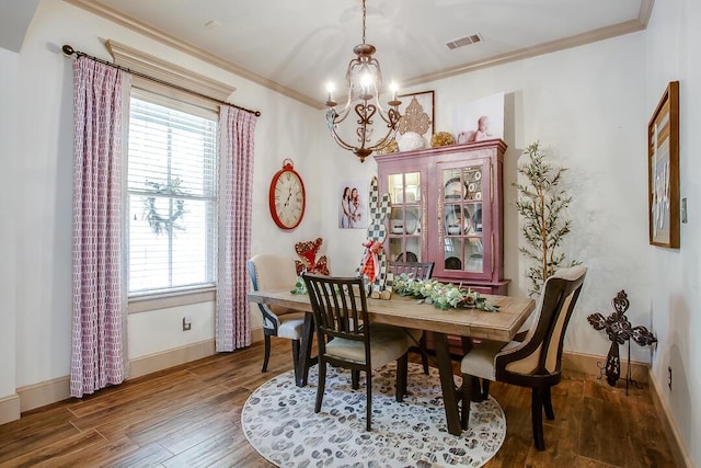 dining area featuring wood finished floors, a chandelier, a wealth of natural light, and visible vents