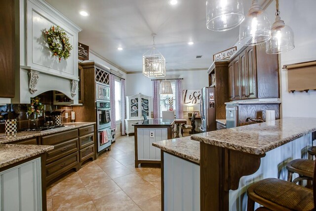 kitchen featuring a chandelier, stainless steel appliances, crown molding, a breakfast bar, and hanging light fixtures