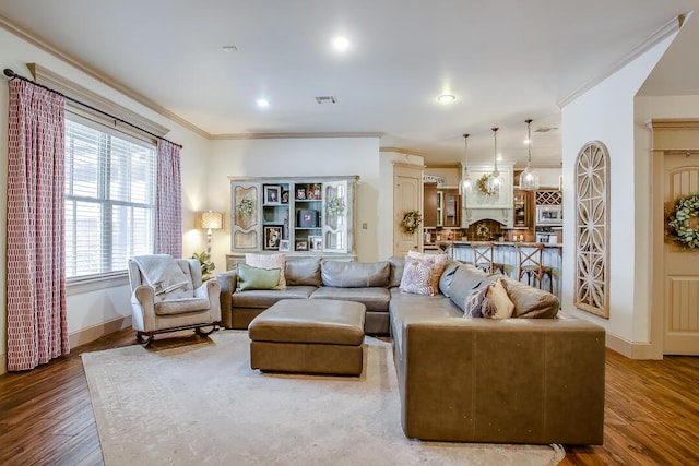 living room featuring baseboards, visible vents, ornamental molding, and wood finished floors