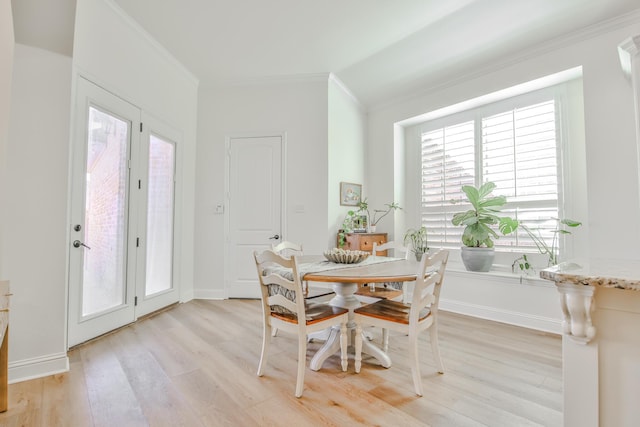 dining room featuring baseboards, ornamental molding, and light wood-style floors